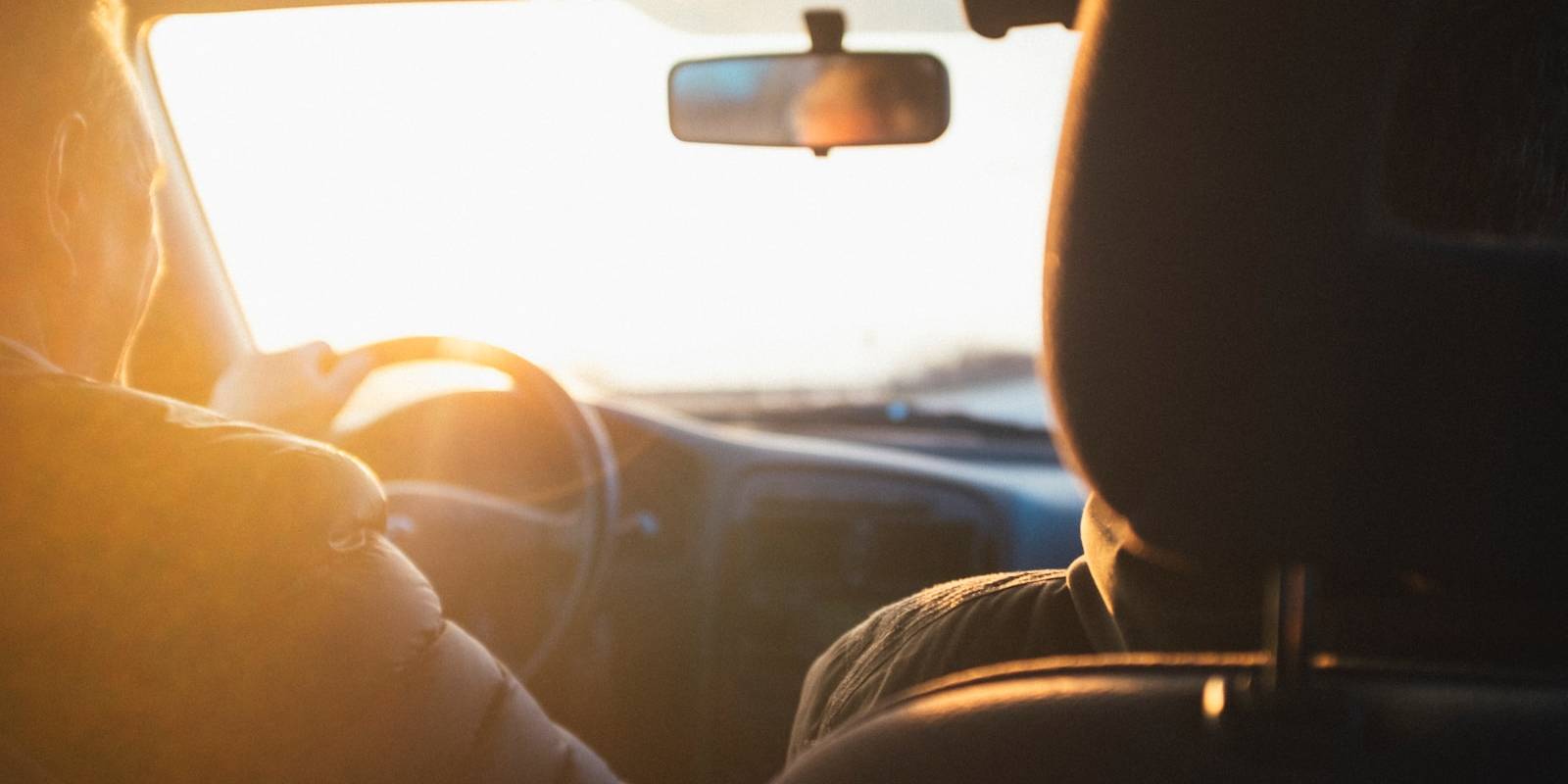 man driving car during golden hour