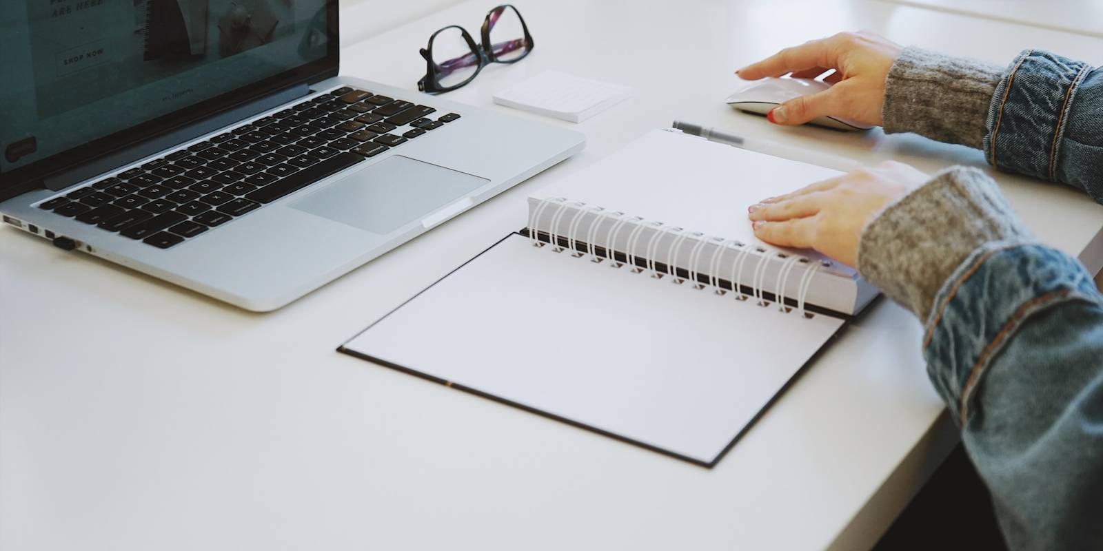 person touching white spiral notebook